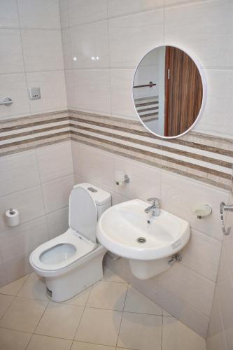 a bathroom with a toilet and a sink and a mirror at Le Cottage Mbale in Mbale
