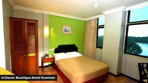 um quarto com uma cama e uma parede verde em Classic Boutique Hotel Kuantan em Kuantan