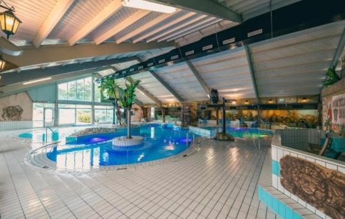 a large swimming pool with blue water in a building at Chalet Panorama near Efteling - with garden and swimmingpool Europarcs in Kaatsheuvel