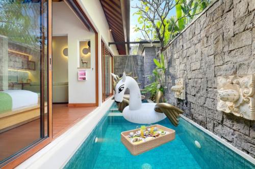 een zwembad met een speelgoedzwaan naast een huis bij Ini Vie Villa Seminyak by Ini Vie Hospitality in Legian