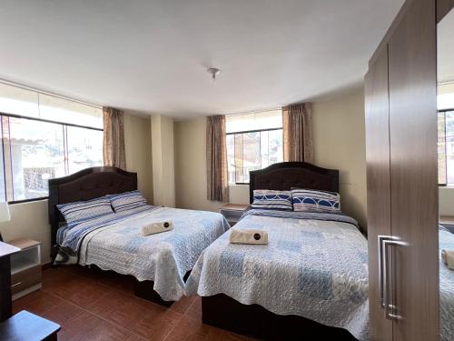 twee bedden in een slaapkamer met twee ramen bij Antara Hostal in Cajamarca