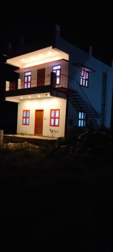 a white house with red doors and stairs at night at Hotel Five Laurels in Yercaud
