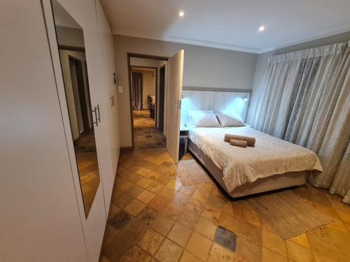 1 dormitorio con cama y pasillo con espejo en 282 Guesthouse/Self-Catering, en Centurion