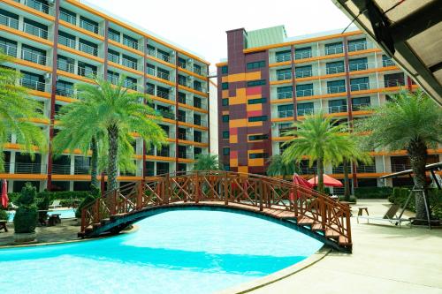 a bridge over a pool with palm trees and buildings at 777 Beach Condo Phuket in Mai Khao Beach