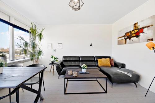 a living room with a black leather couch and a table at Private Scandinavian Apartment in Randers