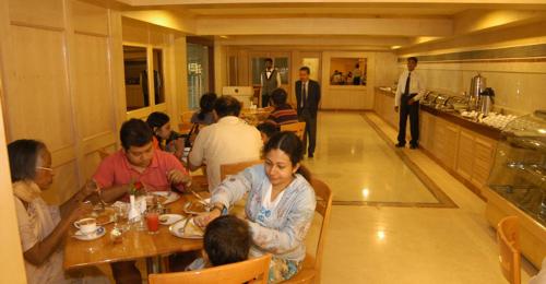 grupa ludzi siedzących przy stole w restauracji w obiekcie Paradise Isle Beach Resort w mieście Udupi