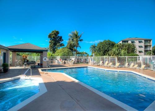 a large swimming pool with chairs and a building at Pacific Shores A-105 - Ground Floor Family Condo in Kihei