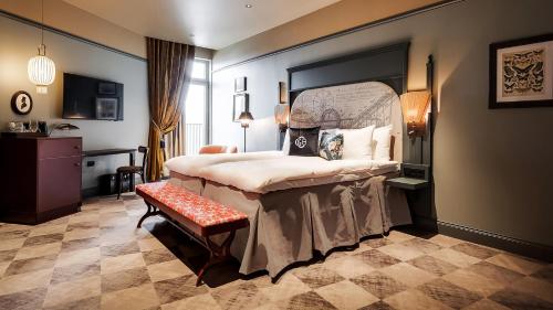 um quarto com uma cama grande e um banco em Liseberg Grand Curiosa Hotel em Gotemburgo