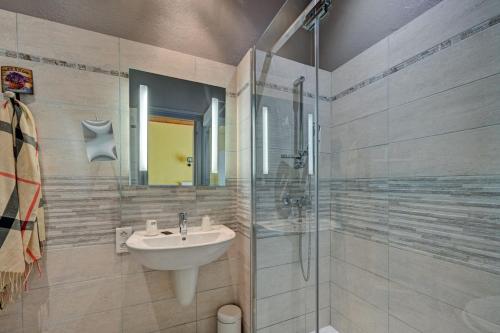 a bathroom with a sink and a glass shower at Hotel Des Artistes in Tarascon