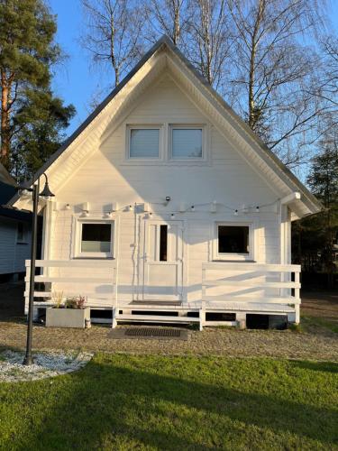 une maison blanche avec un toit en gambrel dans l'établissement Domki nad jeziorem Kazub, à Cieciorka