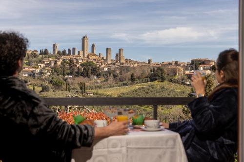 twee mensen zitten aan een tafel en maken foto's van een stad bij B&B La Cornice in San Gimignano