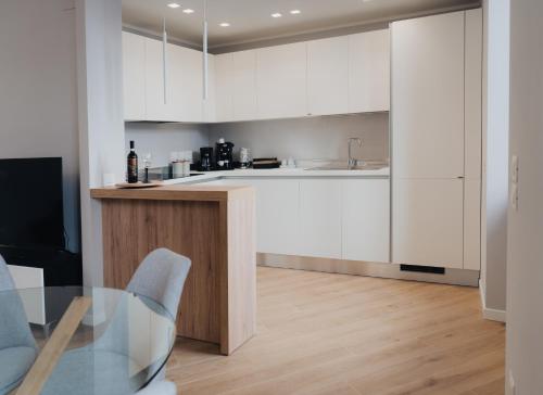 une cuisine avec des placards blancs et une table en verre dans l'établissement Exclusive Apartment in Piazza Italia in Perugia, à Pérouse