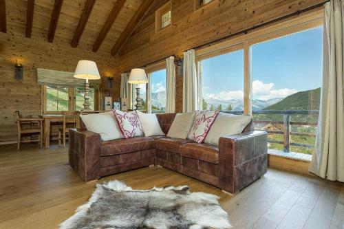 a living room with a couch and a large window at Chalet Jessica in La Tzoumaz