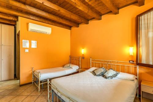 - 2 lits dans une chambre aux murs orange dans l'établissement Agriturismo Pozzo Fiorito, à Castiglione delle Stiviere