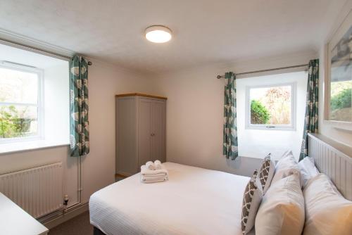 a bedroom with a white bed and two windows at Tregenna Castle Resort in St Ives