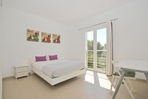 Un dormitorio blanco con una cama y una ventana. en Villa Carritx, en Capdepera