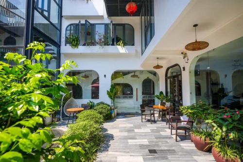 an outdoor patio with tables and chairs and plants at Life Boutique Hotel in Hue