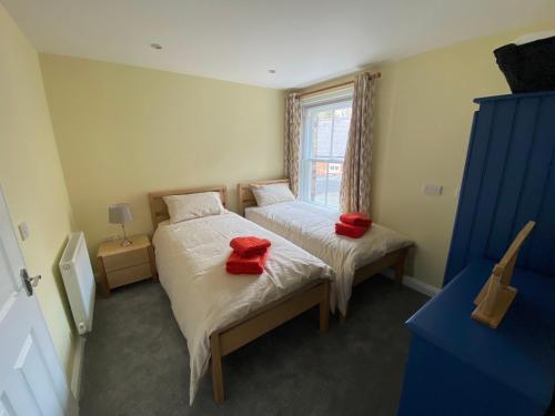 a bedroom with two beds with red pillows on them at Clarendon Luxury Apartment in Woodhall Spa