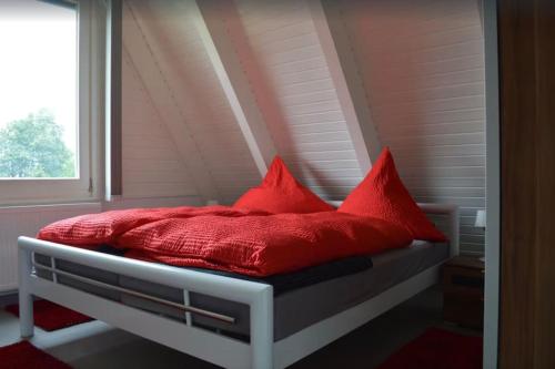 a bed with red pillows on it in a room at Ferienhaus in Waldkatzenbach modern & renoviert in Waldbrunn