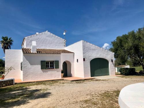 a white house with a green garage at Binimont in Sant Lluis