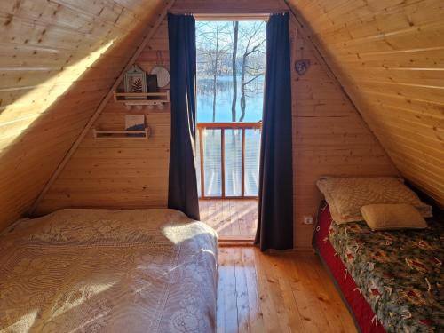 1 dormitorio con 2 camas y una ventana en una cabaña de madera en Mini saunahouse, 