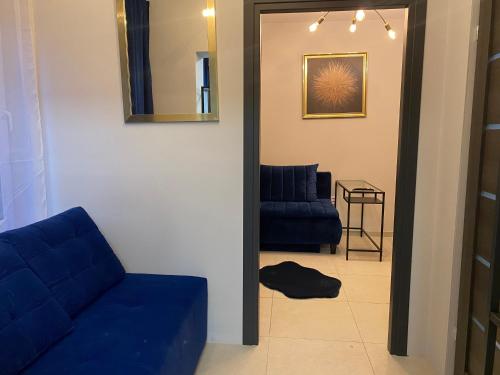 a living room with a blue couch and a mirror at Diament Apartment in Krynica Zdrój