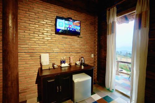uma casa de banho com um lavatório e uma televisão numa parede de tijolos em Lim Village - Nam Ban em Namban