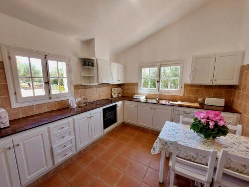 una cocina con armarios blancos y una mesa con flores. en Binimont, en Sant Lluis