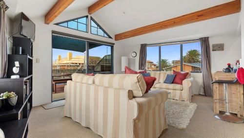 a living room with two couches and a tv at La Maison Ocean - Mount Maunganui Holiday Home in Mount Maunganui
