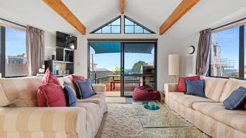 a living room with two couches and a large window at La Maison Ocean - Mount Maunganui Holiday Home in Mount Maunganui
