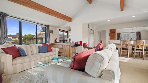 a living room with two white couches and a table at La Maison Ocean - Mount Maunganui Holiday Home in Mount Maunganui