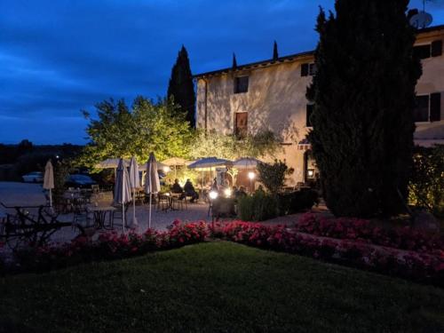 a building with tables and umbrellas in a yard at night at Agriturismo Le Caldane in Colà di Lazise