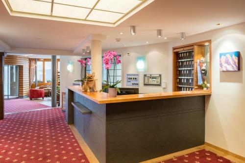 a bar in a hotel lobby with a red carpet at Schweizerhaus Swiss Quality Hotel in Maloja