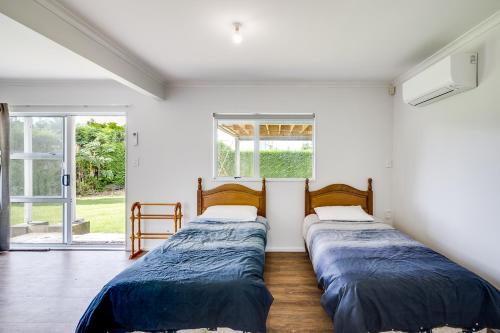 2 Betten in einem Zimmer mit Fenster in der Unterkunft Coastal Haven - Waimarama Holiday Home in Waimarama