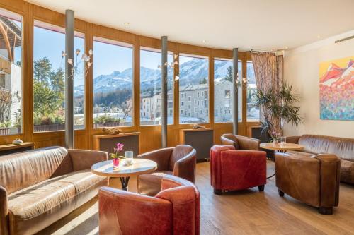 a lobby with couches and tables and large windows at Schweizerhaus Swiss Quality Hotel in Maloja