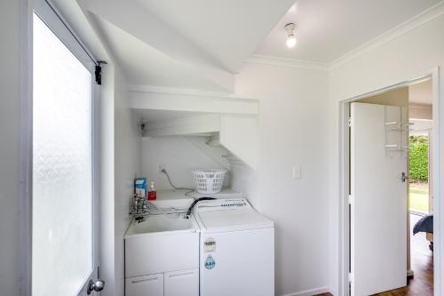eine weiße Waschküche mit Waschmaschine und Trockner in der Unterkunft Coastal Haven - Waimarama Holiday Home in Waimarama