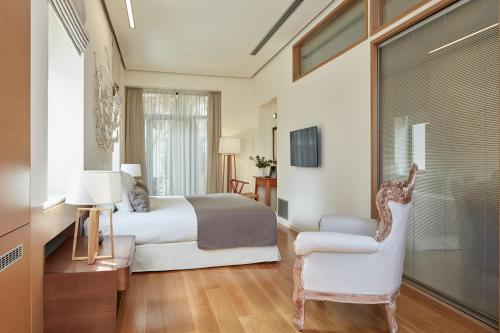 a bedroom with a bed and a chair and a window at Avra City Boutique Hotel in Chania Town