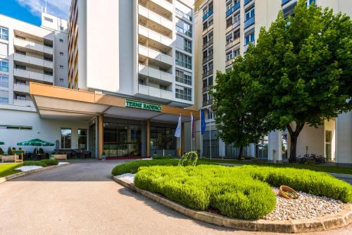 a building with a tree and bushes in front of it at Radenci Spa Resort - Sava Hotels & Resorts in Radenci