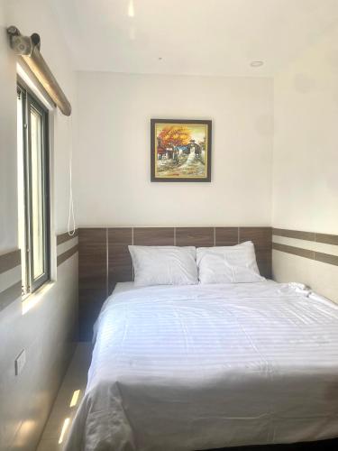 a bedroom with a large white bed and a window at Shine Hotel in Hue