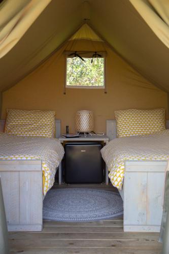 a room with two beds and a tv in a tent at Safaritent Lodge 2 (2 persoons) in Ruurlo