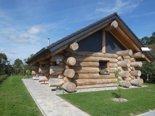 a log cabin with a pile of logs at Naturstammhaus Tollensesee in Krickow