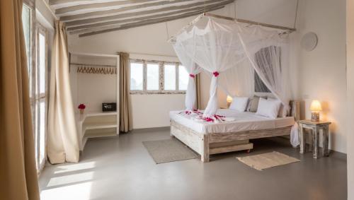a bedroom with a white bed with a canopy at Casamia Suites in Diani Beach