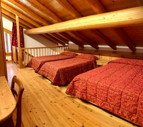 two beds in a room with wooden floors at Baita Oasi Nembia in San Lorenzo in Banale