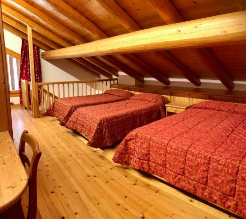 2 camas en una habitación con suelo de madera en Baita Oasi Nembia, en San Lorenzo in Banale