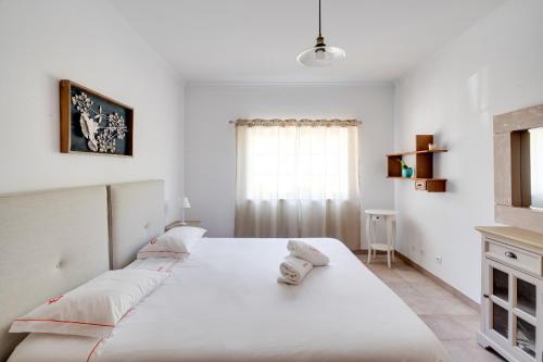 um quarto branco com uma cama grande e uma janela em Na Quinta- alojamento rural com piscina de água salgada em Poceirão