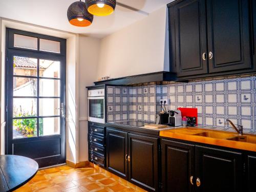 d'une cuisine avec des placards noirs, un évier et une fenêtre. dans l'établissement Le RELAIS DE LEZAT, à Lézat-sur-Lèze