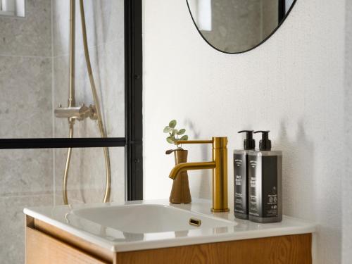 La salle de bains est pourvue d'un lavabo, d'un robinet et d'un miroir. dans l'établissement Sanders Charm - Endearing Two-Bedroom Apartment with Shared Garden, à Copenhague