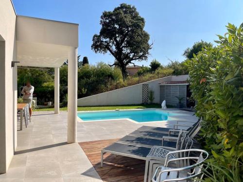 een patio met stoelen en een zwembad bij Villa Cavalaire luxueuse & calme avec piscine in Cavalaire-sur-Mer