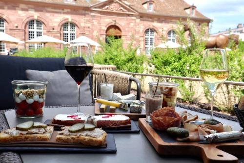 a table with two plates of food and a glass of wine at Hotel Les Haras in Strasbourg