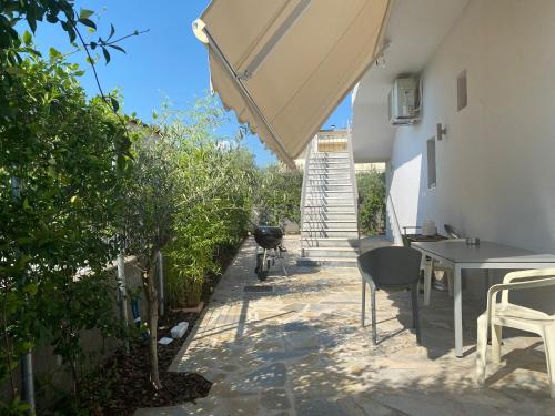 a patio with a table and a grill and an umbrella at Oikos Olympos in Ágios Spyrídon